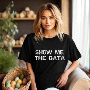 Może przedstawiać: Czarny T-shirt z nadrukiem "SHOW ME THE DATA" w kolorze białym na przodzie.
