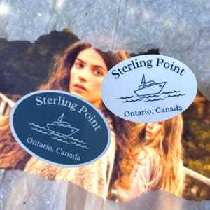 May include: Two oval stickers featuring the text Sterling Point and Ontario, Canada, accompanied by a line art illustration of a boat on waves. One sticker is dark blue with white text, and the other is white with dark blue text and graphics.