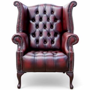 May include: A burgundy leather wingback chair with button detailing on the back and seat. The chair features rolled arms and silver studding. The legs are curved and made of dark wood.