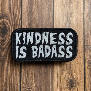 May include: A black embroidered patch with white lettering that reads "Kindness is Badass".
