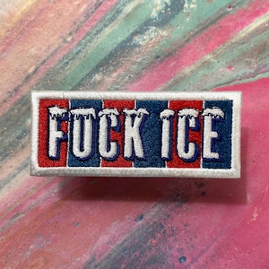 May include: Embroidered patch with the words "FUCK ICE" in white, outlined in red and blue. The patch has a rectangular shape with a white border. The background is a colorful mix of pink, blue, and white.