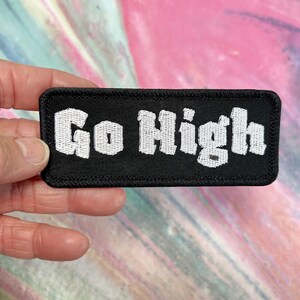 May include: Black fabric patch with white embroidered text that reads "Go High".