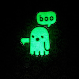 May include: A green glow-in-the-dark ghost with a speech bubble that says "boo" on a black background with a skull pattern.