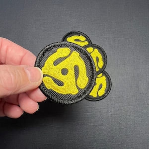 May include: Four black and yellow embroidered iron-on patches with a stylized record logo.