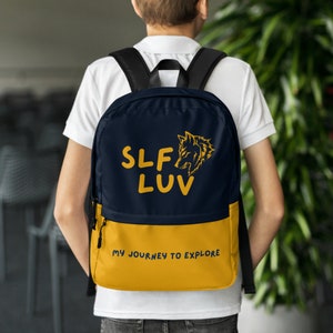 May include: A blue and yellow backpack with a wolf graphic and the text "SLF LUV" on the front. The bottom of the backpack is yellow and has the text "MY JOURNEY TO EXPLORE".