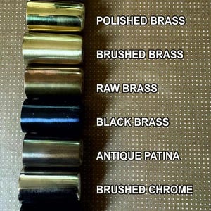 May include: A collection of cylindrical metal samples in various finishes, including polished chrome, polished brass, brushed brass, raw brass, black brass, antique patina, brushed chrome, and matte black. Text labels identify each finish.