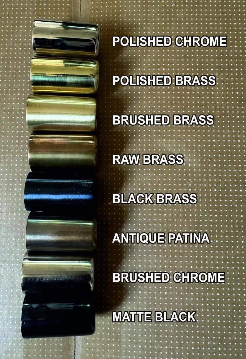 May include: A collection of cylindrical metal samples in various finishes, including polished chrome, polished brass, brushed brass, raw brass, black brass, antique patina, brushed chrome, and matte black. Text labels identify each finish.