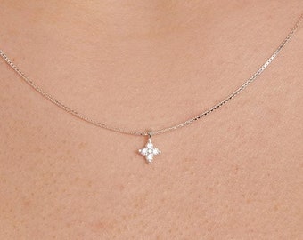 May include: A silver chain necklace with a small, four-pronged pendant set with clear cubic zirconia stones.
