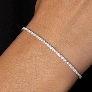May include: A delicate silver bracelet with a row of small, clear cubic zirconia stones.