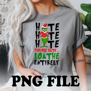 May include: A grey t-shirt featuring a green Grinch character wearing a Santa hat. The text on the shirt reads "Hate Hate Hate Double Hate... Loathe Entirely".