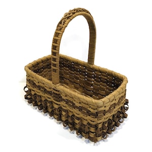 May include: A brown woven basket with a handle and a decorative trim around the top and bottom. The basket is made of natural materials and has a rustic look.