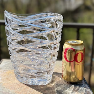 May include: A clear glass vase with a criss-cross pattern. The vase is about the size of a standard can of soda.