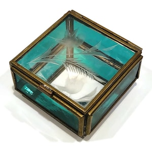 May include: A small, square, teal glass trinket box with a brass frame and etched floral design.