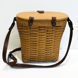 May include: A brown wicker basket with a leather strap and a wooden lid. The basket is oval shaped and has a woven pattern.