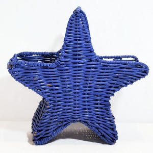 May include: A blue woven wicker star-shaped basket with a handle. The basket is made of woven wicker and is painted a solid blue color.