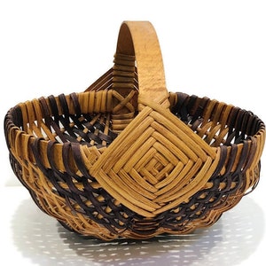 May include: A small, brown and natural woven basket with a wooden handle. The basket has a diamond pattern woven into the front.