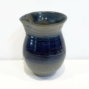 May include: A blue and gray ceramic pitcher with a rounded body and a wide, slightly flared lip.