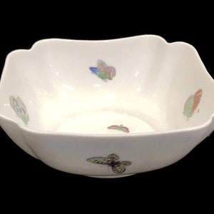 May include: A white porcelain bowl with a square shape and scalloped edges. The bowl is decorated with colorful butterfly designs.