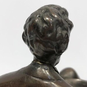 May include: A bronze sculpture of a person's head and shoulders. The sculpture is detailed and shows the person's hair and facial features.