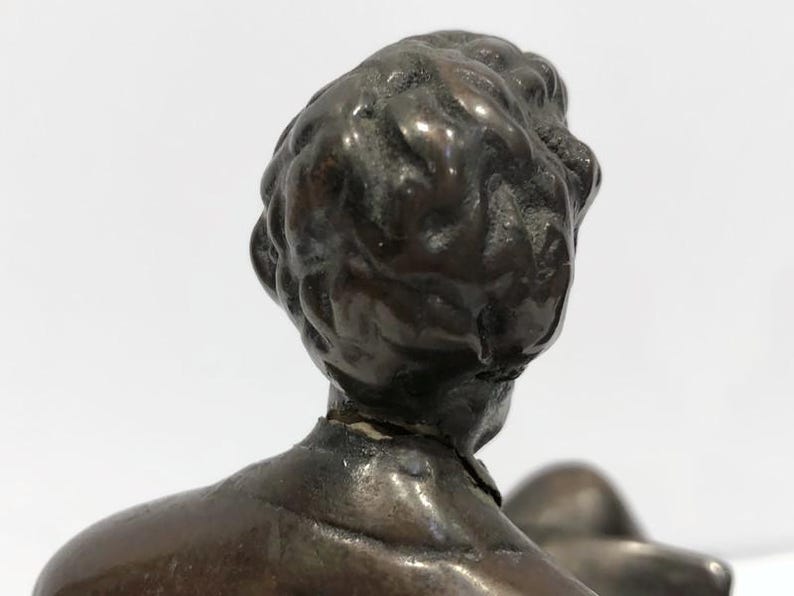 May include: A bronze sculpture of a person's head and shoulders. The sculpture is detailed and shows the person's hair and facial features.