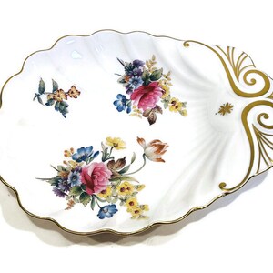 May include: White porcelain serving dish with a scalloped edge and gold trim. The dish features a floral design with pink, red, yellow, and blue flowers.