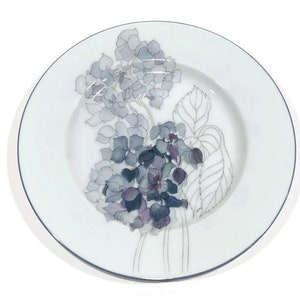 May include: A white ceramic plate with a silver rim features a hand-painted design of a bouquet of purple and gray hydrangeas.