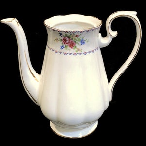 May include: White porcelain coffee pot with a gold trim and floral pattern. The pot has a scalloped rim and a delicate floral design with pink, blue, and green flowers.