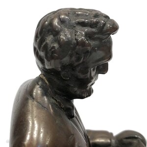 May include: A bronze sculpture of a man's head and shoulders. The man is wearing a suit jacket and has a serious expression on his face.