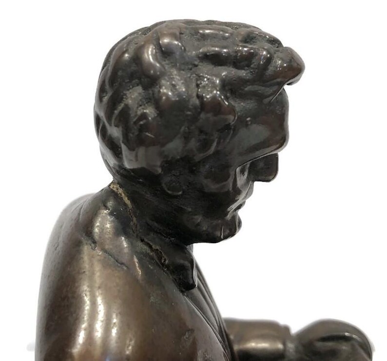 May include: A bronze sculpture of a man's head and shoulders. The man is wearing a suit jacket and has a serious expression on his face.