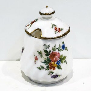 May include: White porcelain sugar bowl with a lid and a floral design. The lid has a gold trim and a small spout. The bowl is decorated with colorful flowers and leaves.