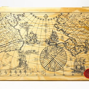 May include: A wooden box with a nautical map design featuring ships, a globe, and a compass. The box has a red wax seal with the letter "W" on it.
