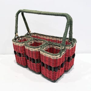 May include: A red and green woven wicker basket with a handle. The basket has four compartments and black beads around the edges.