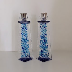Puede incluir: Un par de candelabros de vidrio con parte superior plateada y detalles en vidrio azul y blanco. Los candelabros tienen forma de rectángulo alto y delgado.