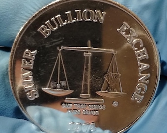 May include: Silver bullion exchange coin with a scale design. One troy ounce pure silver 1974.