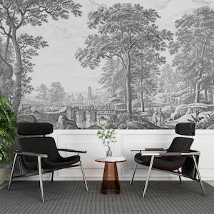 May include: Two black leather chairs with metal frames and a small glass table in front of a black and white wall mural depicting a landscape with trees, a bridge, and a building.
