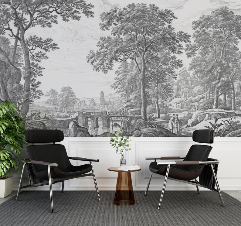 May include: Two black leather chairs with metal frames and a small glass table in front of a black and white wall mural depicting a landscape with trees, a bridge, and a building.