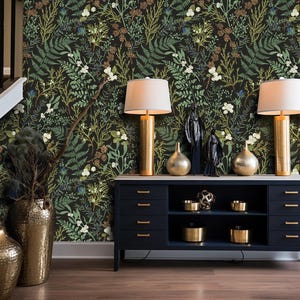 May include: A black dresser with four drawers and two shelves, decorated with gold-colored lamps, vases, and decorative objects. The dresser is in front of a wall with a dark green floral wallpaper.