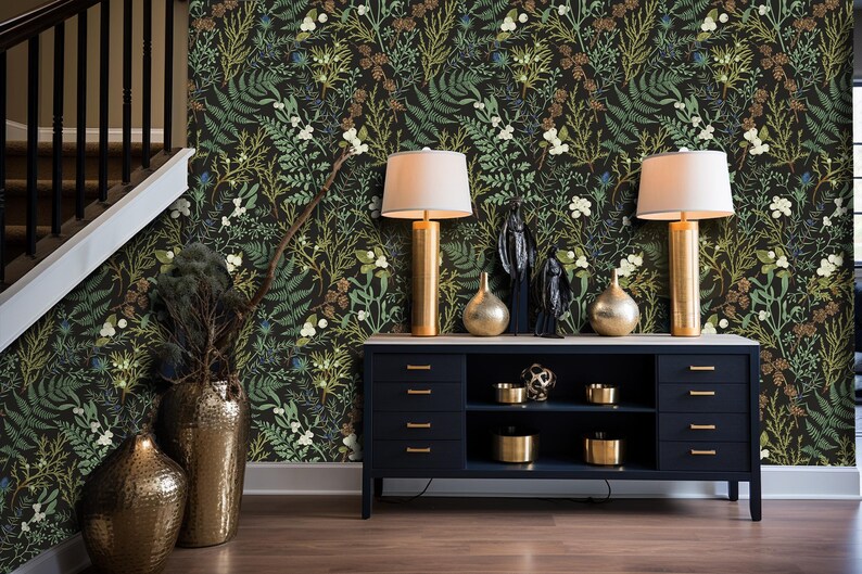 May include: A black dresser with four drawers and two shelves, decorated with gold-colored lamps, vases, and decorative objects. The dresser is in front of a wall with a dark green floral wallpaper.