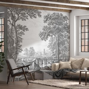 May include: A black and white photo print of a landscape scene with trees, a bridge, and a building in the distance. The print is framed and hanging on a wall in a living room.
