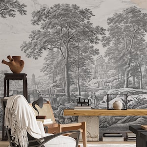 May include: A black and white vintage illustration of a landscape with trees, a bridge, and a building in the distance. The illustration is printed on a wall mural, which is displayed in a living room setting with a chair, a table, and other decor.
