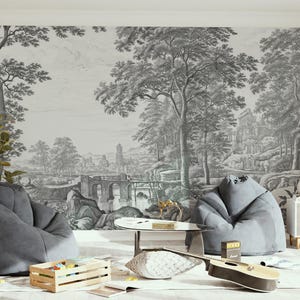 May include: A living room interior with two gray bean bag chairs, a wooden coffee table, and a guitar on the floor. The wall features a black and white print of a landscape with trees and a bridge.