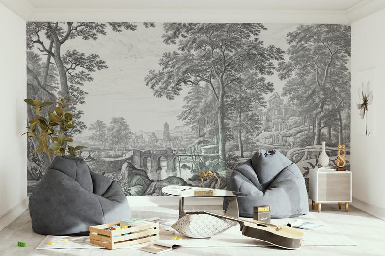 May include: A living room interior with two gray bean bag chairs, a wooden coffee table, and a guitar on the floor. The wall features a black and white print of a landscape with trees and a bridge.