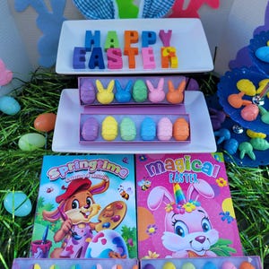 May include: A set of Easter-themed crayons in the shape of eggs and bunnies. The crayons are arranged in two boxes, one with the words "Springtime Coloring & Activity" and the other with the words "Magical Easter".