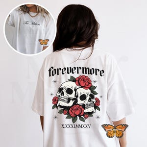 May include: White t-shirt with a graphic on the back featuring two skulls, red roses, and the word "forevermore" in gothic font. The front of the shirt has the text "The Millers" and a butterfly graphic. A butterfly graphic is also on the sleeve.