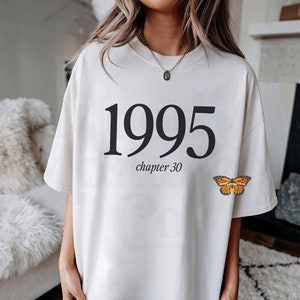 May include: White oversized t-shirt with black text that reads "1995 chapter 30" and a small orange butterfly graphic.