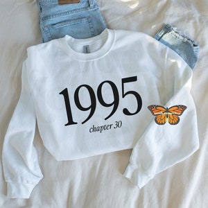 May include: White sweatshirt with black text that says "1995 chapter 30". A monarch butterfly is on the right sleeve.