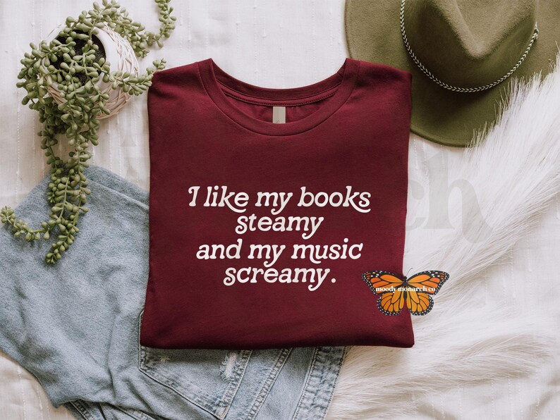 May include: A maroon t-shirt with the text "I like my books steamy and my music screamy." printed in white.