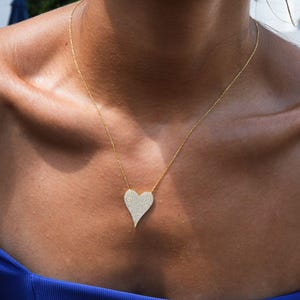 May include: A gold chain necklace with a large, sparkling, diamond-encrusted heart pendant.