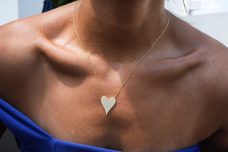 May include: A gold chain necklace with a large, sparkling, diamond-encrusted heart pendant.
