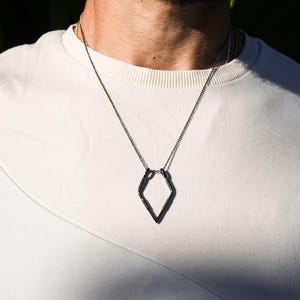 May include: A silver chain necklace with a geometric diamond-shaped pendant.